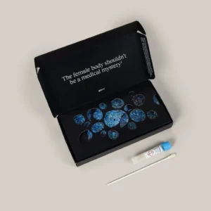 An open black box with the text "The female body shouldn't be a medical mystery!" contains a kit with blue patterned items, next to a swab and a sample vial on a beige surface. , Kiara Health Fertility