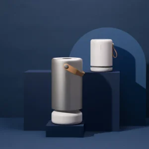 Two modern, cylindrical Molekule speakers with leather straps are displayed on dark blue geometric platforms against a solid blue background, blending elegant design inspired by air purifier aesthetics. , Kiara Health Fertility