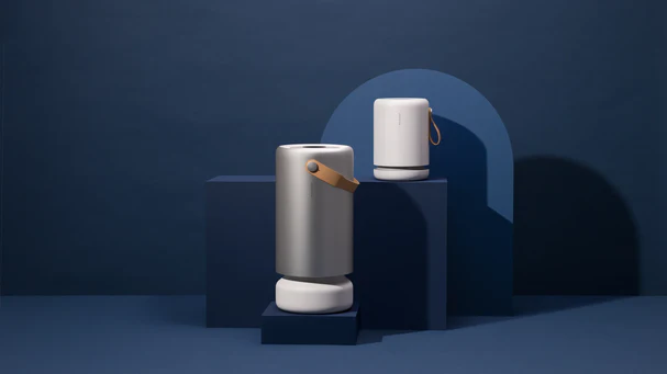 Two modern, cylindrical Molekule speakers with leather straps are displayed on dark blue geometric platforms against a solid blue background, blending elegant design inspired by air purifier aesthetics. , Kiara Health Fertility