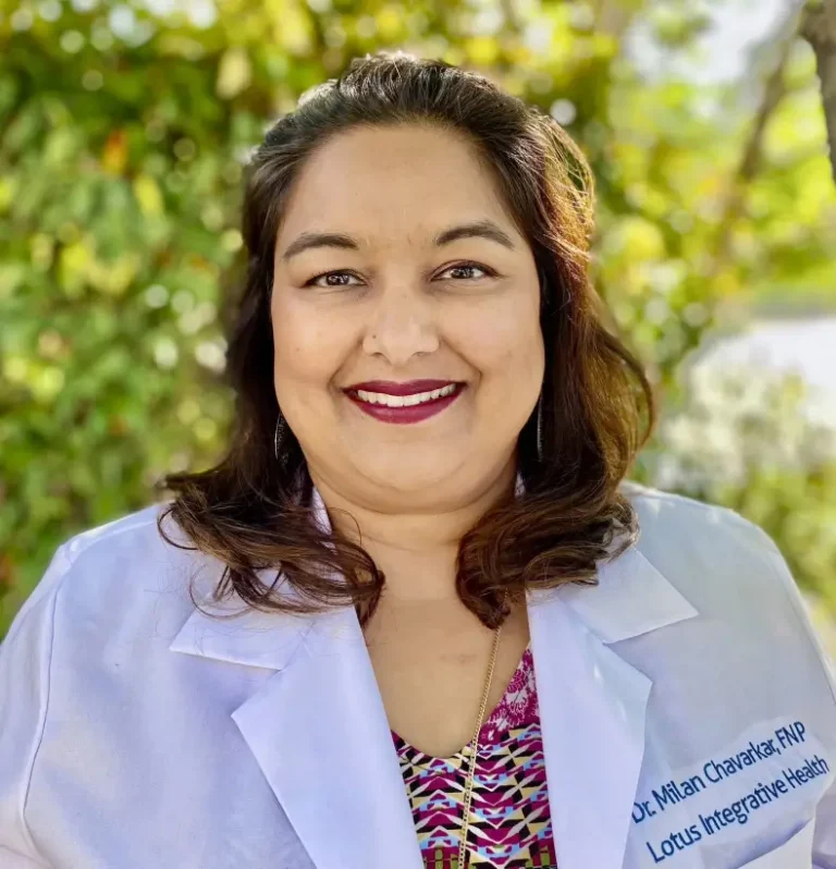 A woman wearing a white medical coat stands outdoors, smiling, with green foliage in the background, inviting you to discover more about her Free Coaching Session. , Kiara Health Fertility