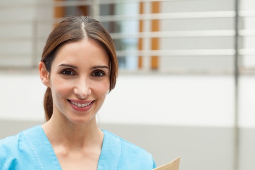Woman in blue scrubs smiling at the camera, holding a folder, standing indoors with a blurred background—perfect for use on a professional Landing Page or as featured imagery for Landing Page 7.2. , Kiara Health Fertility